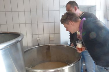 Interessierte Blicke in einen Kessel voller Bier