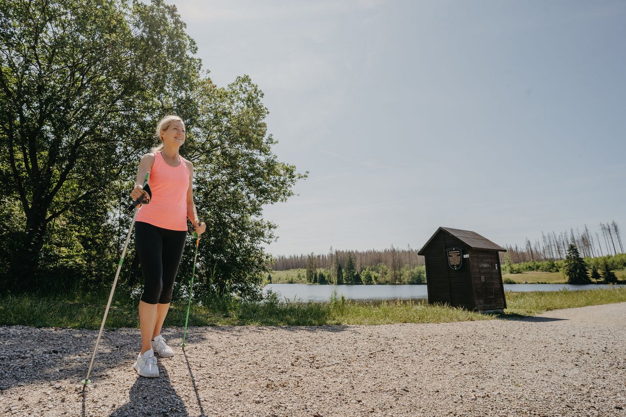 Nordic Walking Läuferin steht auf dem Weg an einem See