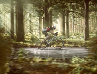 Rennradfahrer fährt auf einem Weg durch einen Wald