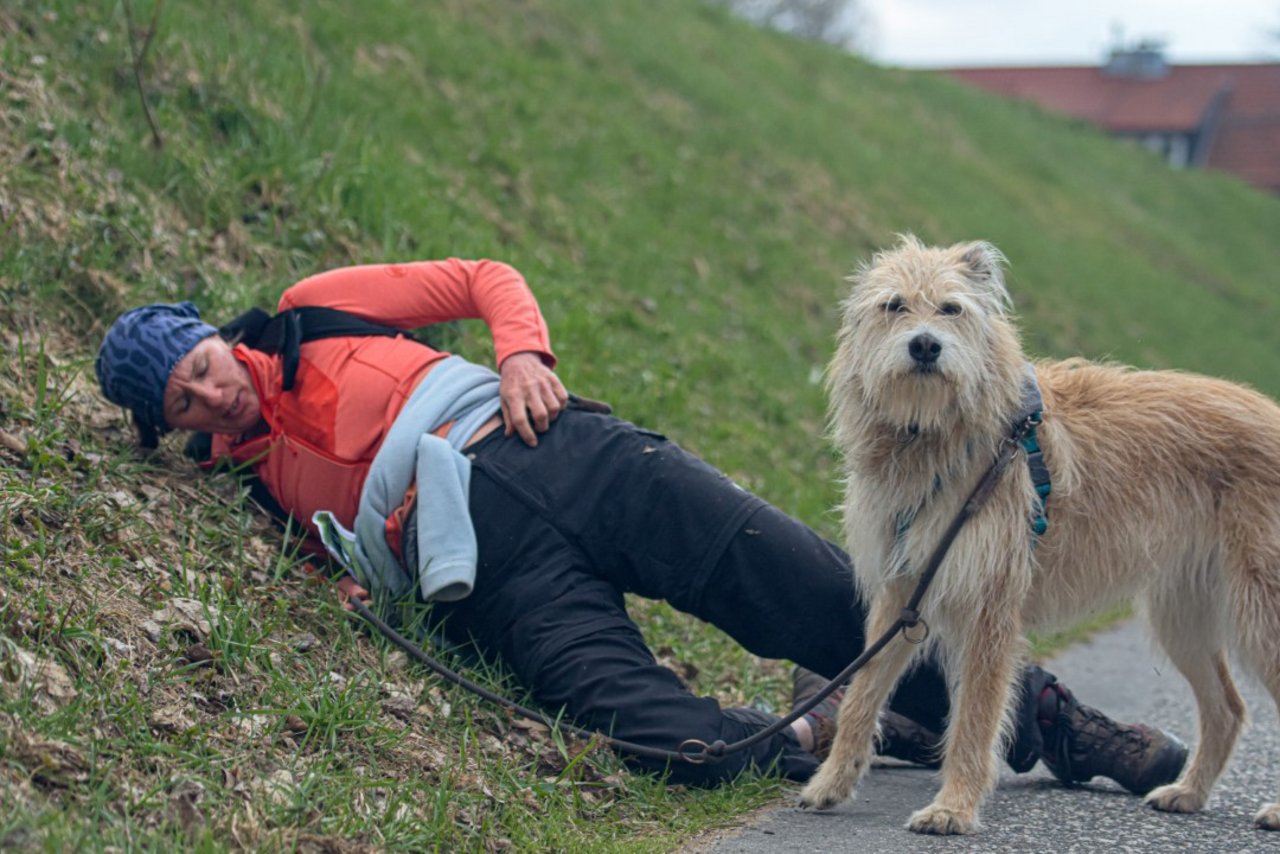 Teilnehmerin liegt auf Wiese, Hund steht daneben 