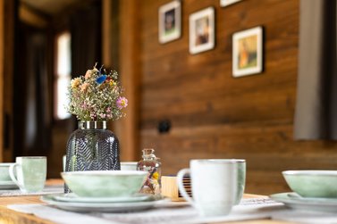 Gedeckter Tisch in der Harz Urlaubs Alm mit einem Deko-Blumenstrauß im Fokus
