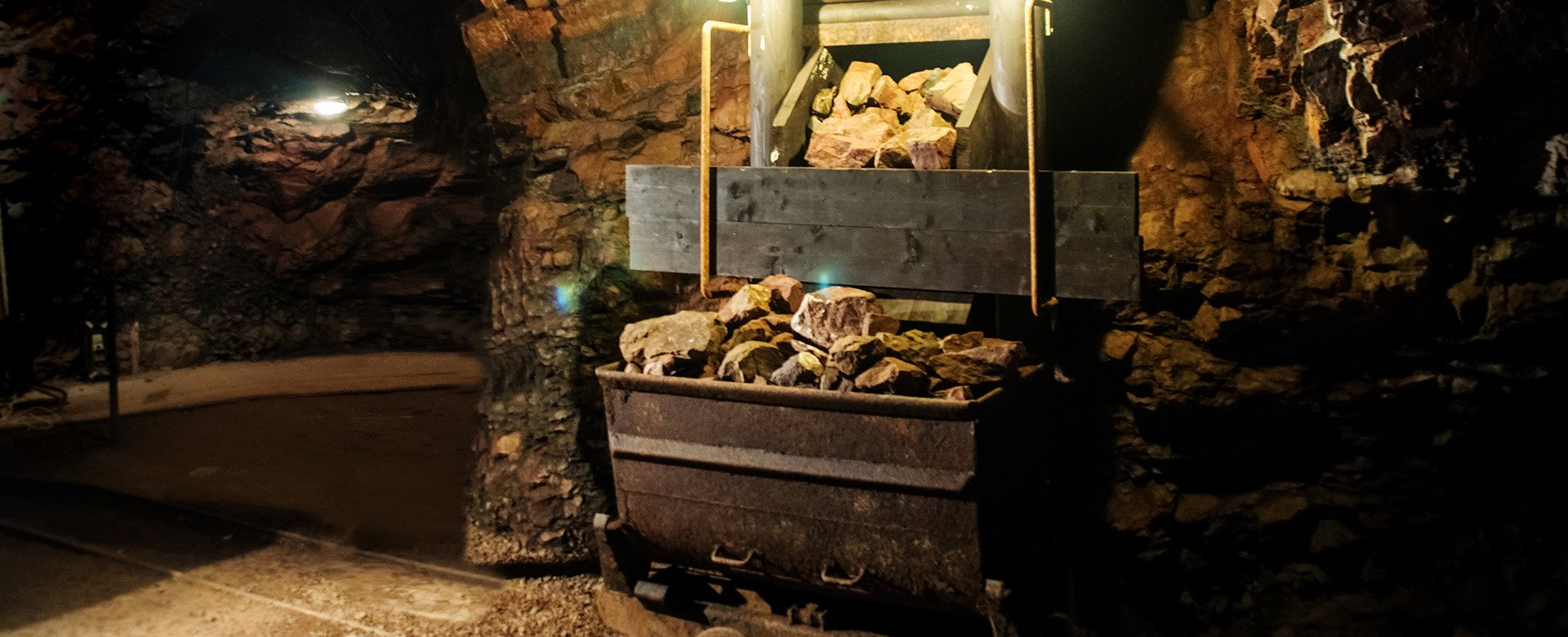 Eine mit Steinen gefüllte Lore steht in einem Stollen
