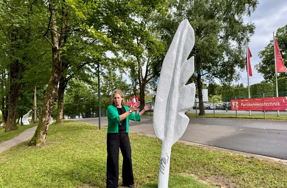 große Feder-Skulptur mit Frau daneben