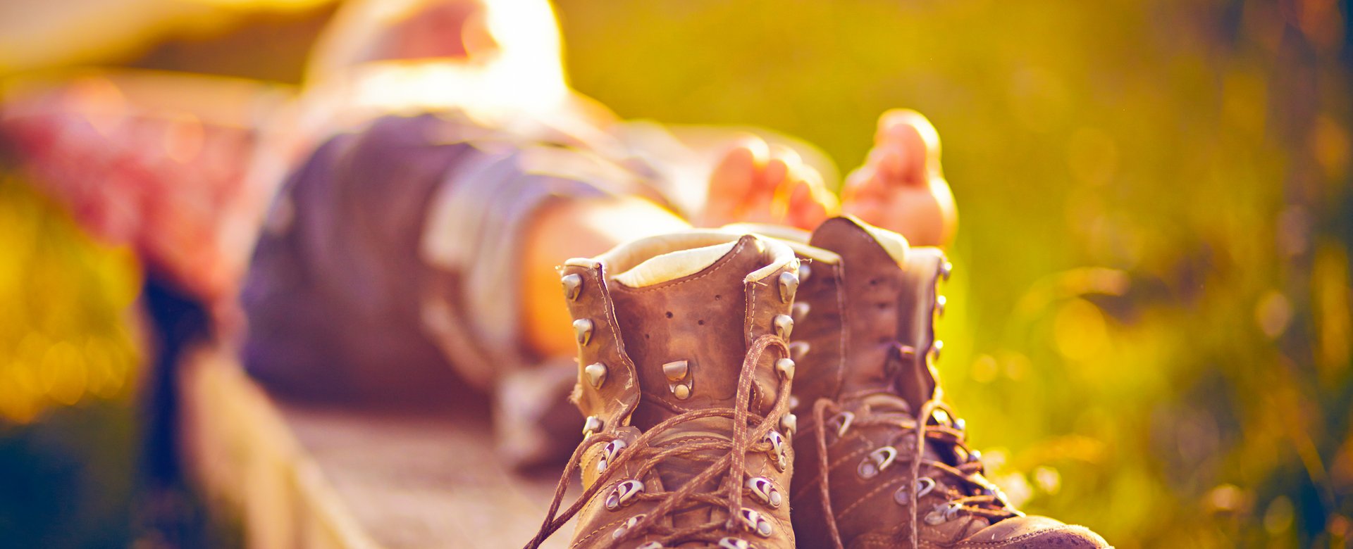 Wanderer der sich gerade auf einer Bank ausruht, im Fokus seine Wanderstiefel