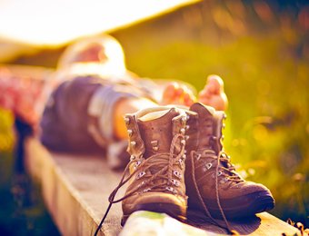 Wanderer der sich gerade auf einer Bank ausruht, im Fokus seine Wanderstiefel