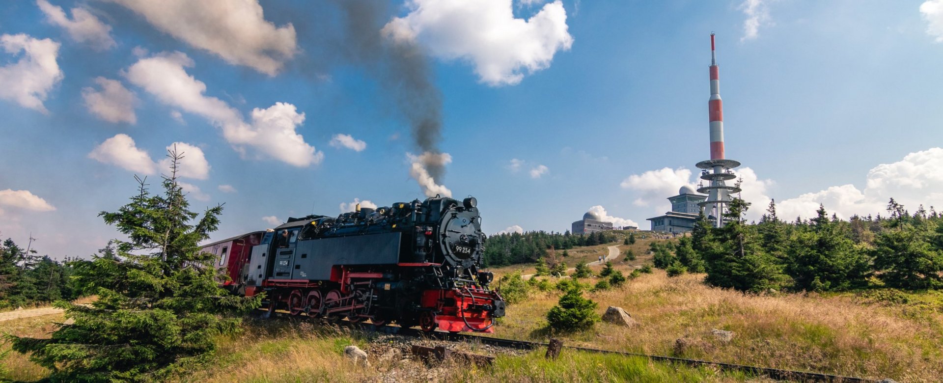 Brockenbahn fährt dampfend auf den Brocken bei sonnigem Wetter