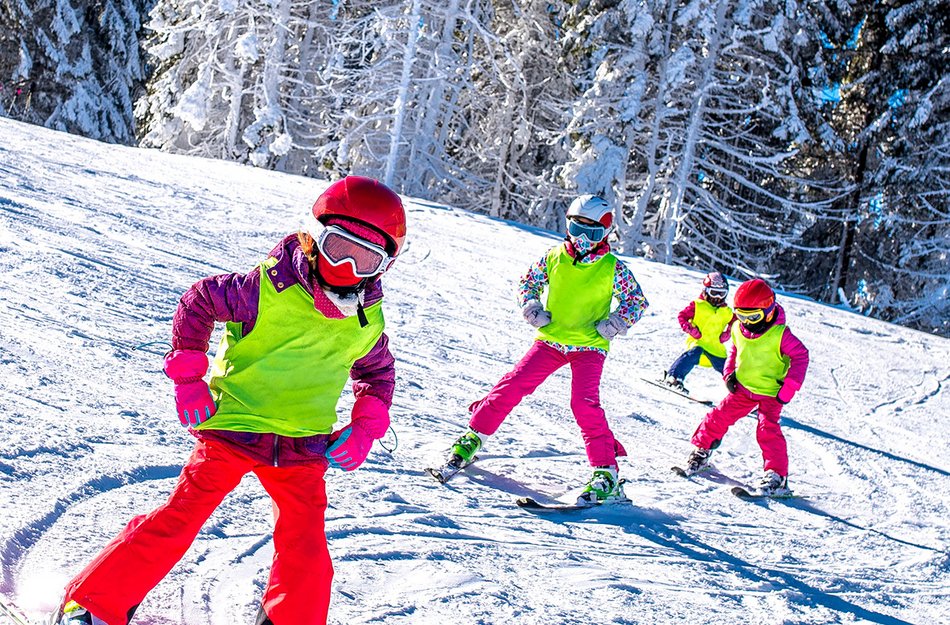 Vier Kinder auf Ski fahren eine Strecke entlang