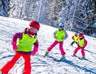 Vier Kinder auf Ski fahren eine Strecke entlang