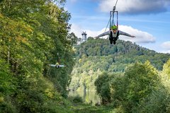 Blick auf die Zipline Strecke mit 2 Personen welche diese fahren