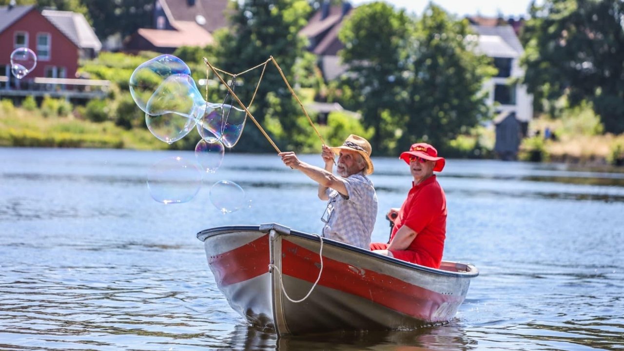 Mann fährt im Boot und macht große Seifenblasen