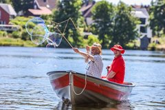 Mann fährt im Boot und macht große Seifenblasen