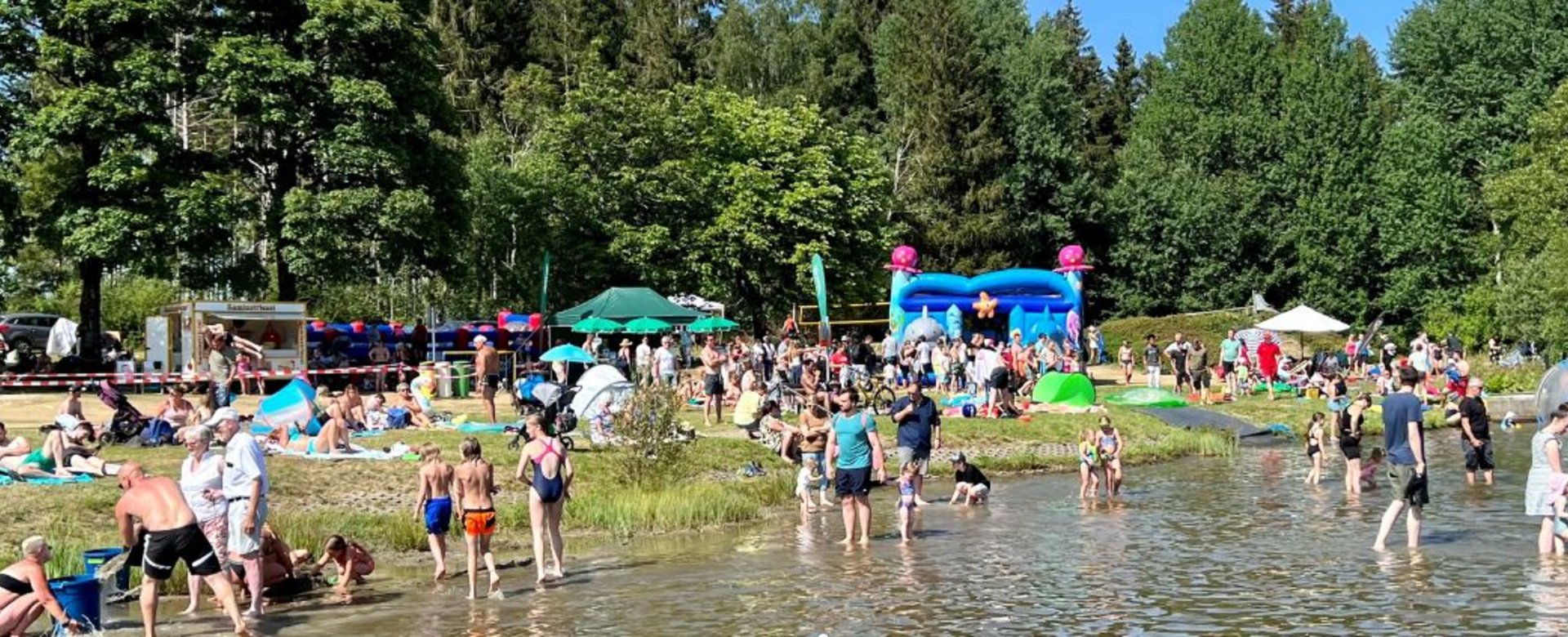 Blick auf viele Leute im Wasser und an Land im Waldseebad