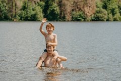 Vater mit Sohn auf den Schultern steh in einem See