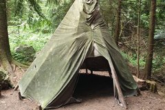 selbstgebauter Shelter aus Stöckern und einer Plane im Wald