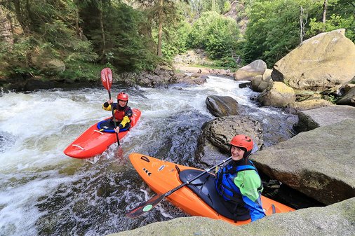Mann und Frau auf Wildwasserstrecke in kleinen Kanus