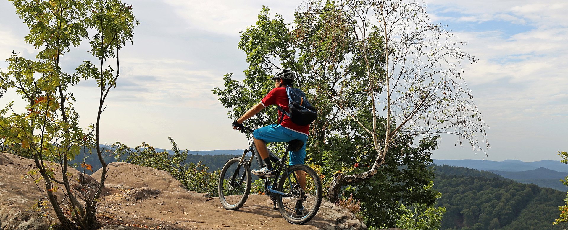 Mountainbiker steht auf einem Felsen und schaut in die Ferne