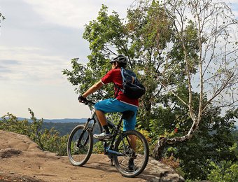 Mountainbiker steht auf einem Felsen und schaut in die Ferne