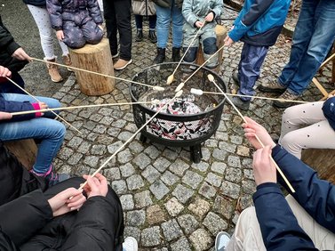Menschen backen Stockbrot über dem Feuer