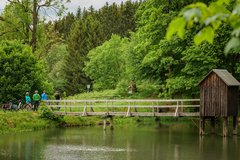 Radfahrer machen eine Pause neben einem kleinen Teich inmitten eines Waldes
