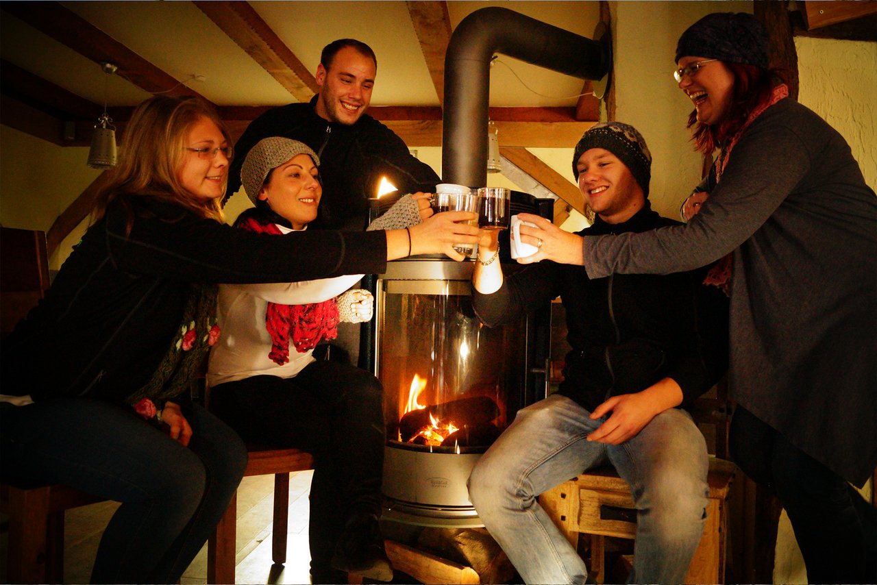 Menschen stoßen an vor dem Kamin