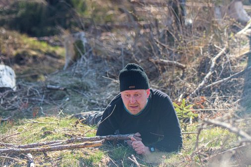 Mann robbt auf Waldboden