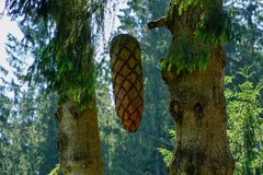 Geschnitzter Tannenzapfen hängt im Baum 