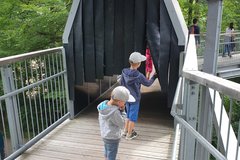 Kinder laufen durch einen halb verdeckten Tunnel auf dem Baumwipfelpfad