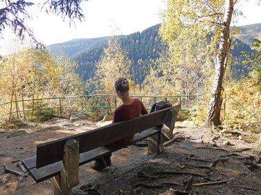 Frau sitzt auf Bank und genießt Ausblick