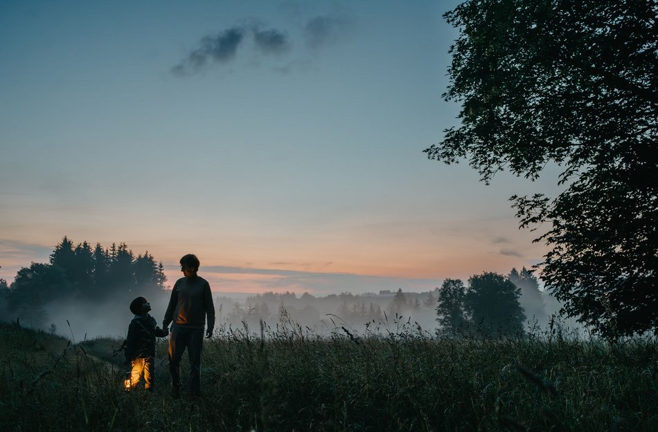 Vater und Sohn mit Laterne im Morgenrot in einer vernebelten Landschaft im Oberharz
