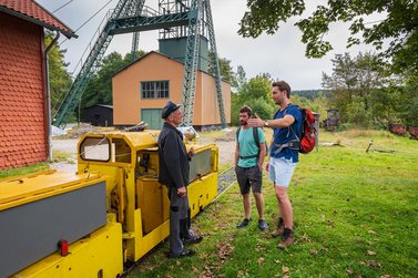 2 Wanderer unterhalten sich mit Mitarbeiter des Ottiliae-Schacht vor dem Gelände
