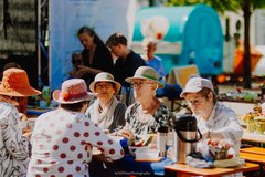 Gäste sitzen mit Sonnenhut am Tisch beim Bürgerfrühstück 