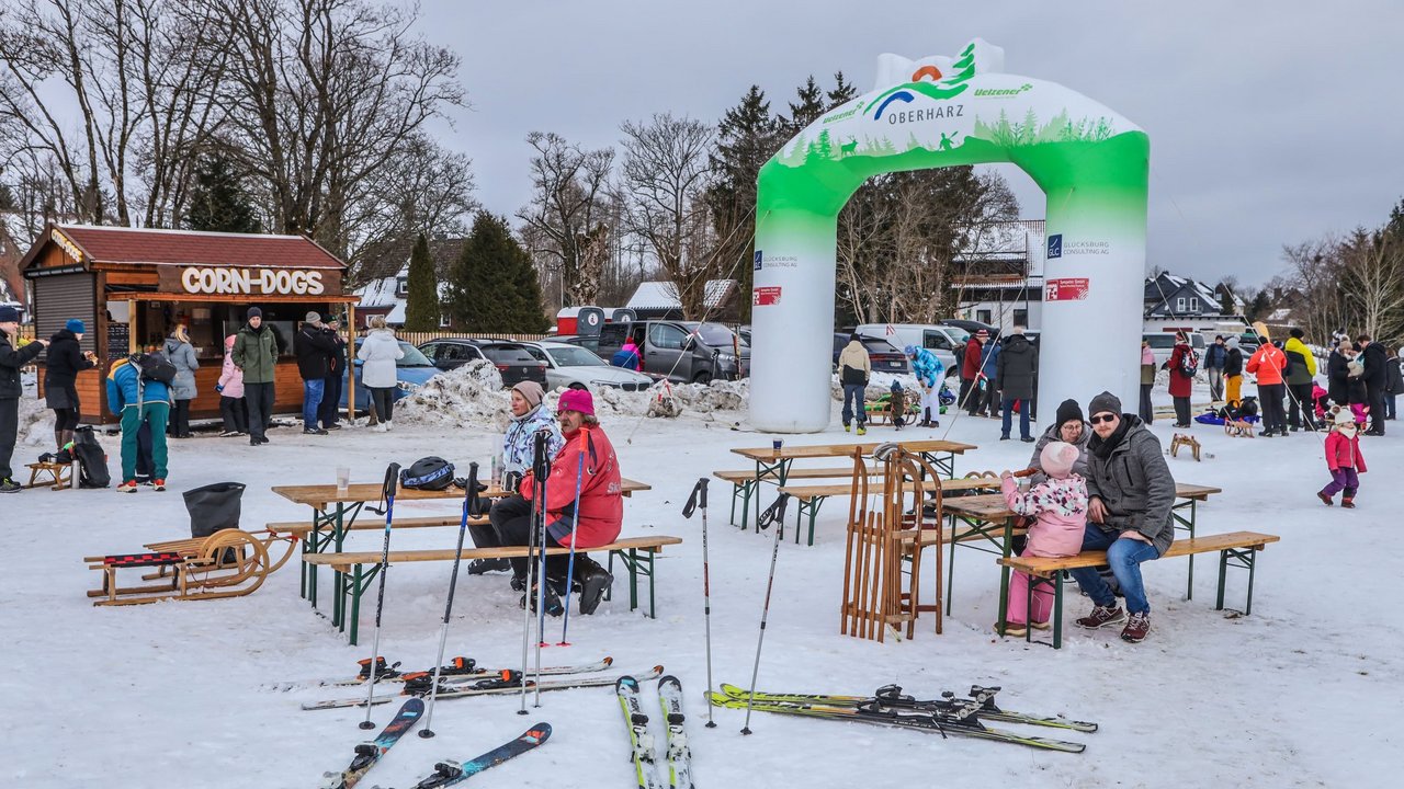 Wintergaudi auf der Skiwiese: Leute sitzen auf Bank und ruhen aus 