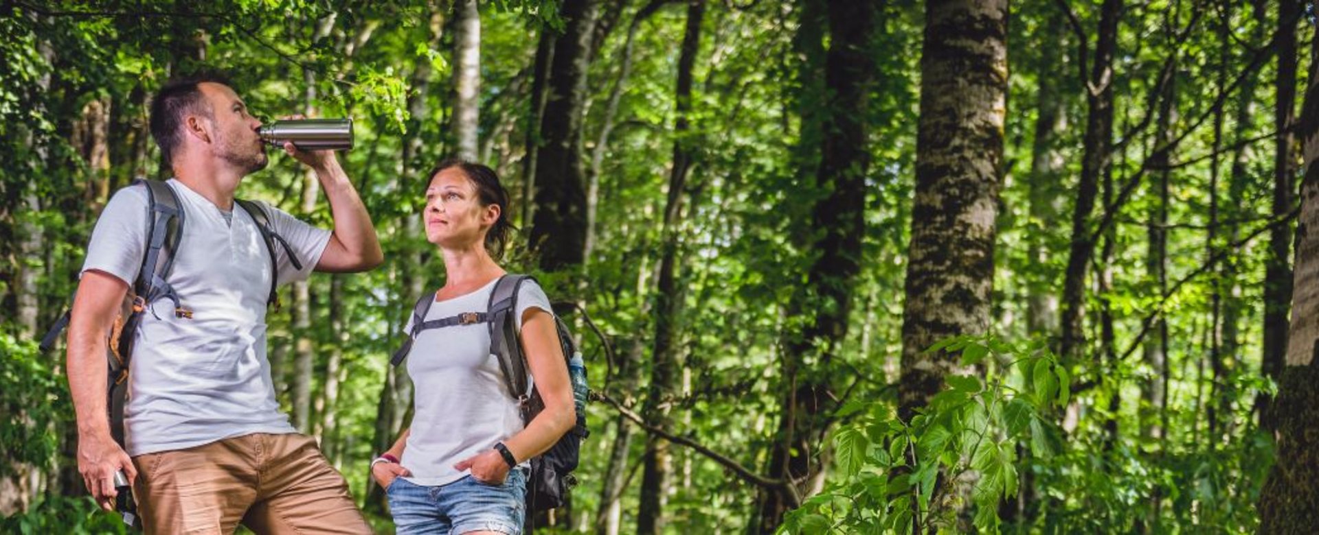 Zwei Männer trinken aus ihrer Flasche im Wald