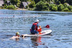Mensch paddelt mit SUP auf dem Teich