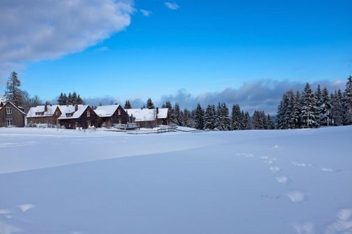 Blick über verschneite Wiese zum Torfhaus Harzresort 
