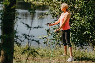 Nordic-Walking Läuferin steht an einem See