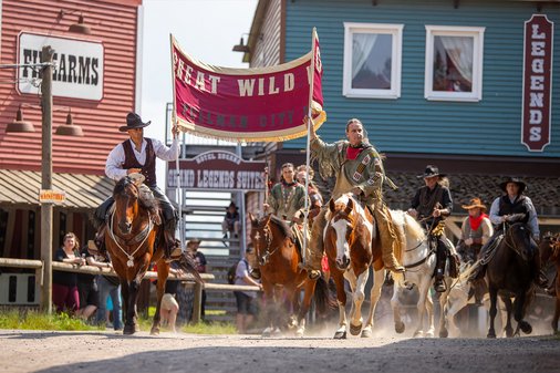 Indianer und Cowboy halten zusammen auf Pferden ein Banner in der Pullman City Show