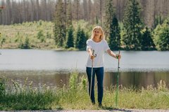 Eine Nordic-Walking Läuferin geht an einem Teich entlang