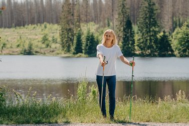 Eine Nordic-Walking Läuferin geht an einem Teich entlang