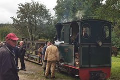 Personen vor der Bergbau-Bahn welche gerade parkt
