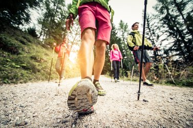 Nahaufnahme eines Nordic Walking Wanderers mit weiteren Personen beim walken im Hintergrund
