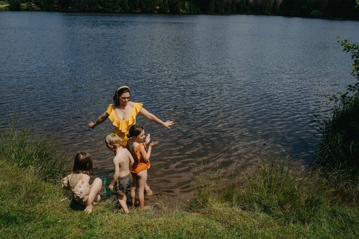 Mutter mit drei Kindern steht Fußtief im Wasser am See