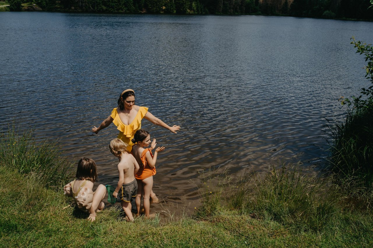 Mutter mit drei Kindern steht Fußtief im Wasser am See