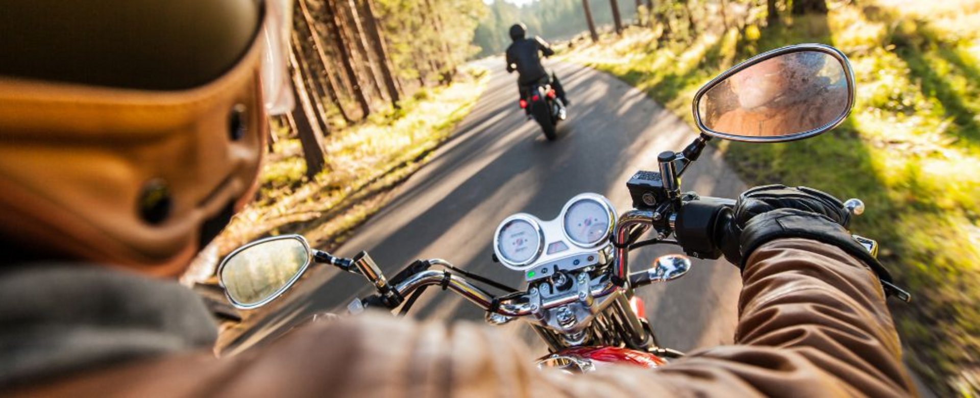 Motorradfahrer auf Straße im Wald