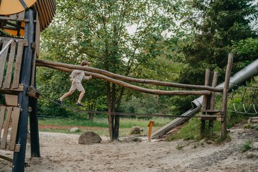 Junge rennt über Brücke auf dem Robinson Abenteuer Spielplatz