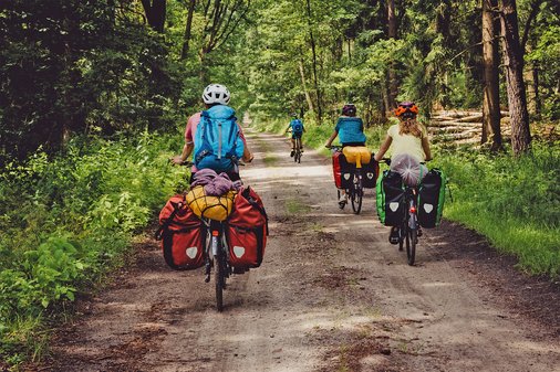 Viele schwer bepackte Fahrradfahrer fahren durch einen Wald 