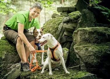 Hund und Frau sitzen an Felsen